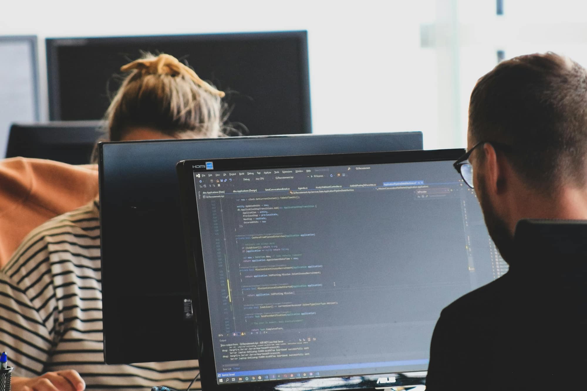 Two developers working through code on the same monitor